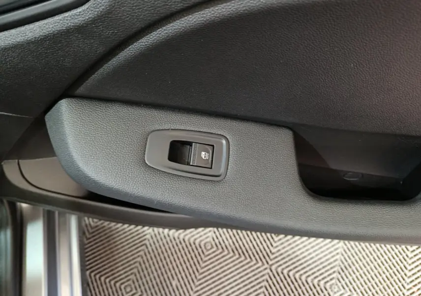 Gros plan sur le bouton de verrouillage centralisé sur la porte intérieure côté conducteur d'une Renault Clio gris foncé.