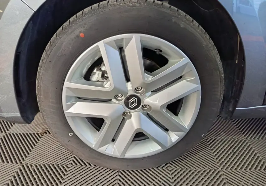 Gros plan sur la roue avant gauche de la Renault Clio gris foncé, mettant en valeur la jante aluminium au design moderne.