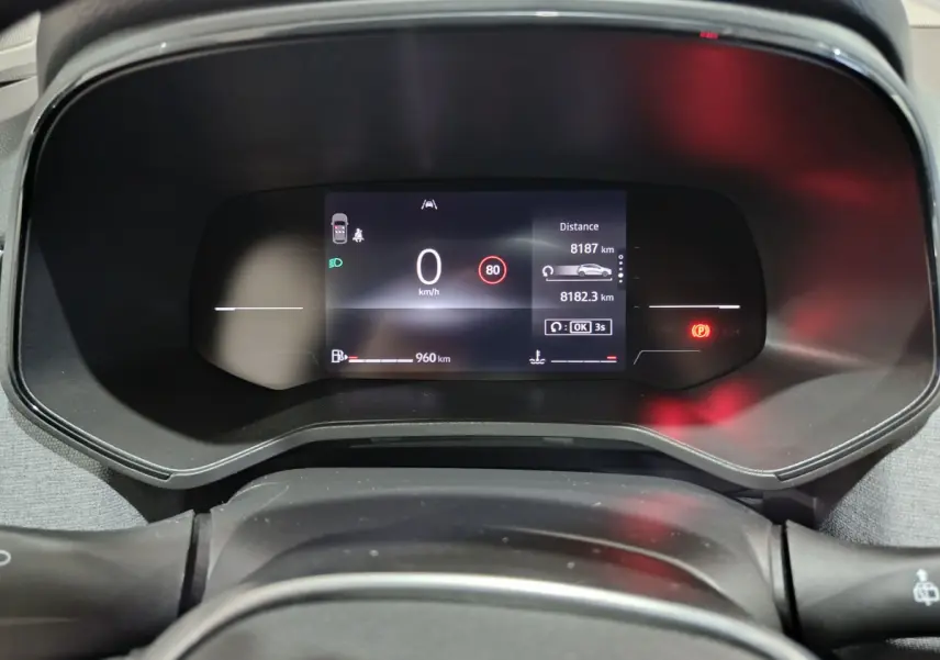 Tableau de bord numérique de la Renault Clio gris foncé 2025 affichant la vitesse, autonomie et alertes au centre du combiné d'instruments.