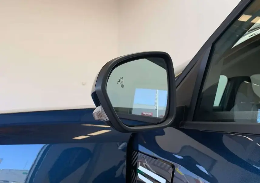 Rétroviseur côté gauche du Dacia Bigster bleu indigo avec toit noir, montrant le détecteur d'angle mort intégré.