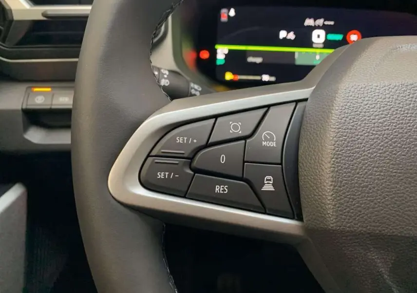 Gros plan sur les commandes au volant cuir du DACIA BIGSTER Hybrid 155, avec tableau de bord digital en arrière-plan.