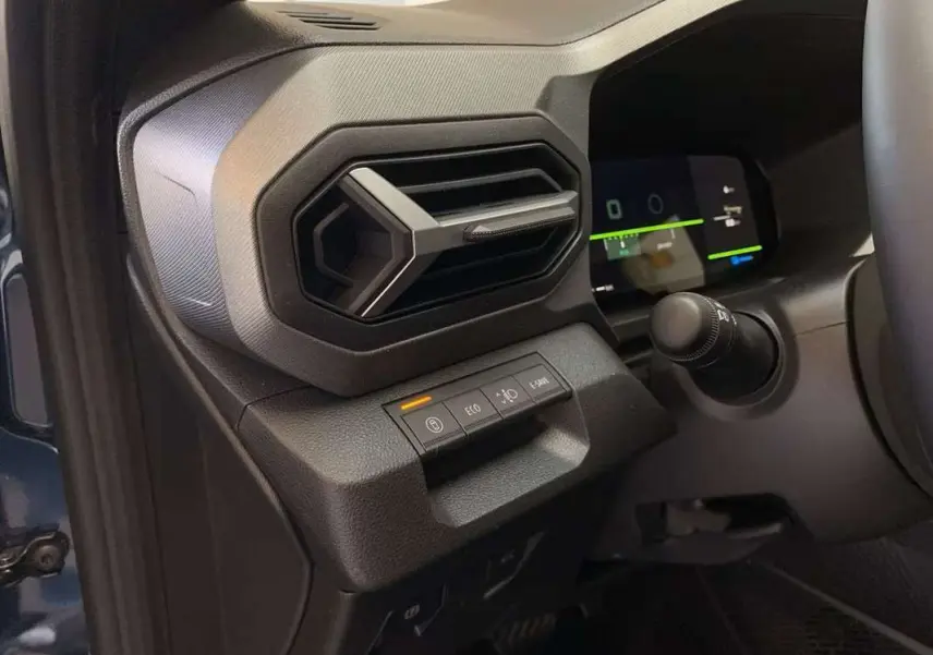 Détail de la console gauche avec aérateur hexagonal et commandes sur fond noir du Dacia Bigster Hybrid 155 bleu indigo.