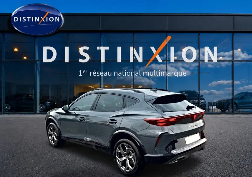 Vue 3/4 arrière droite d'un CUPRA Formentor gris métallisé garé devant une vitrine Distinxion.