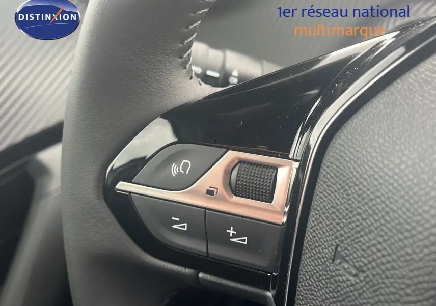 Gros plan sur les commandes du volant d'une Peugeot 2008 blanche, mettant en valeur les boutons de volume et de téléphone.