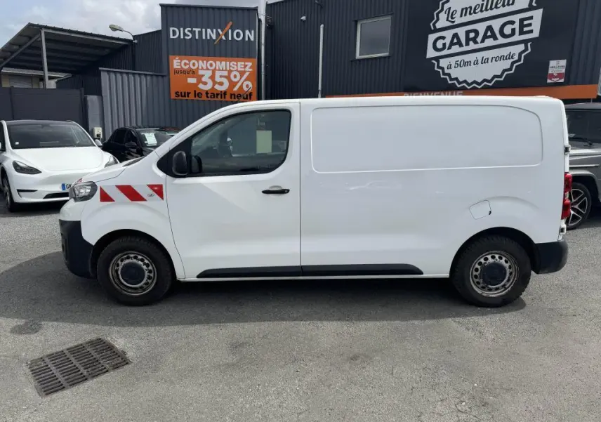 Profil droit d'un utilitaire blanc Peugeot Expert Fourgon 2018 avec bandes rouges diagonales sur l'aile avant.