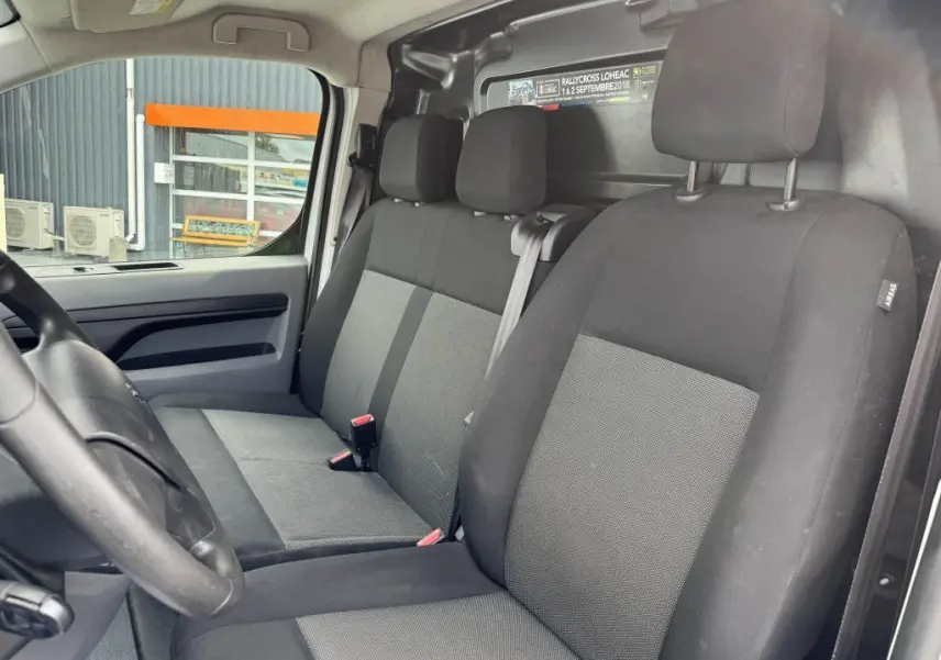 Vue intérieure côté conducteur du Peugeot Expert Fourgon 2018 avec sièges tissu tri-ton noir et gris et cloison tôlée arrière.