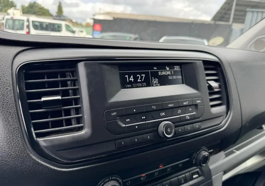Vue rapprochée du tableau de bord noir du Peugeot Expert Fourgon blanc, mettant en valeur l'écran radio et les commandes centrales.