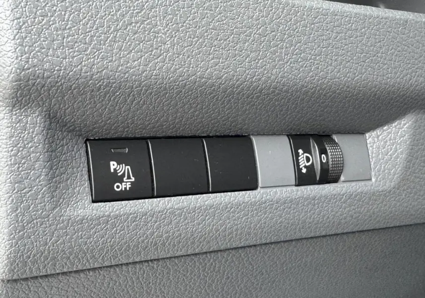 Gros plan sur les commandes de réglage des feux et désactivation du radar de stationnement du Peugeot Expert Fourgon blanc.