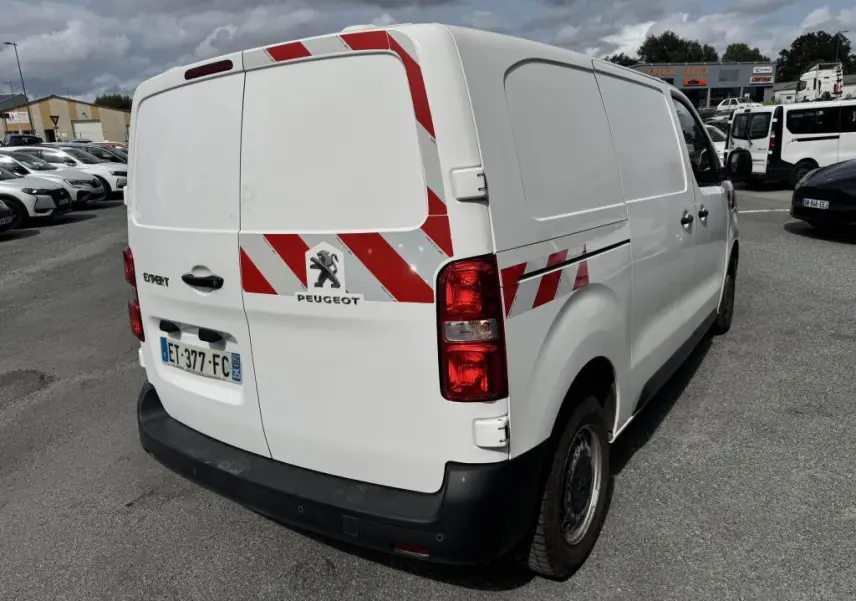 Vue 3/4 arrière droite du Peugeot Expert Fourgon blanc avec bandes réfléchissantes rouges et blanches sur portes et flanc.