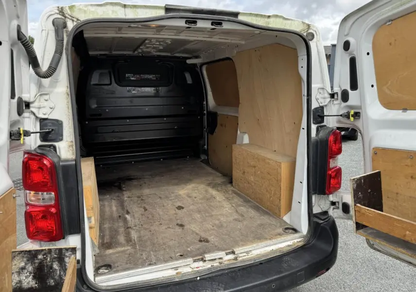 Vue arrière ouverte du Peugeot Expert Fourgon blanc avec intérieur de chargement en bois et plancher usé visible.
