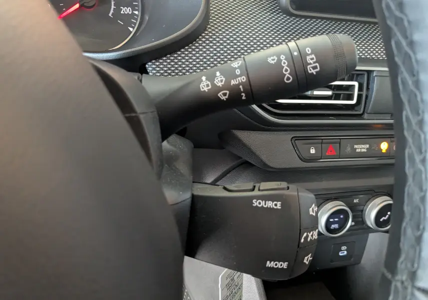 Gros plan sur la commande multifonction et le commodo d’essuie-glace du tableau de bord du Dacia Jogger 2025, intérieur noir.