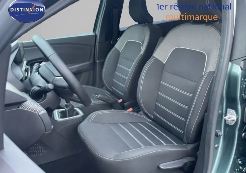 Vue intérieure centrée sur la console centrale du Dacia Jogger 2025, montrant la boîte manuelle et les sièges en tissu noir.