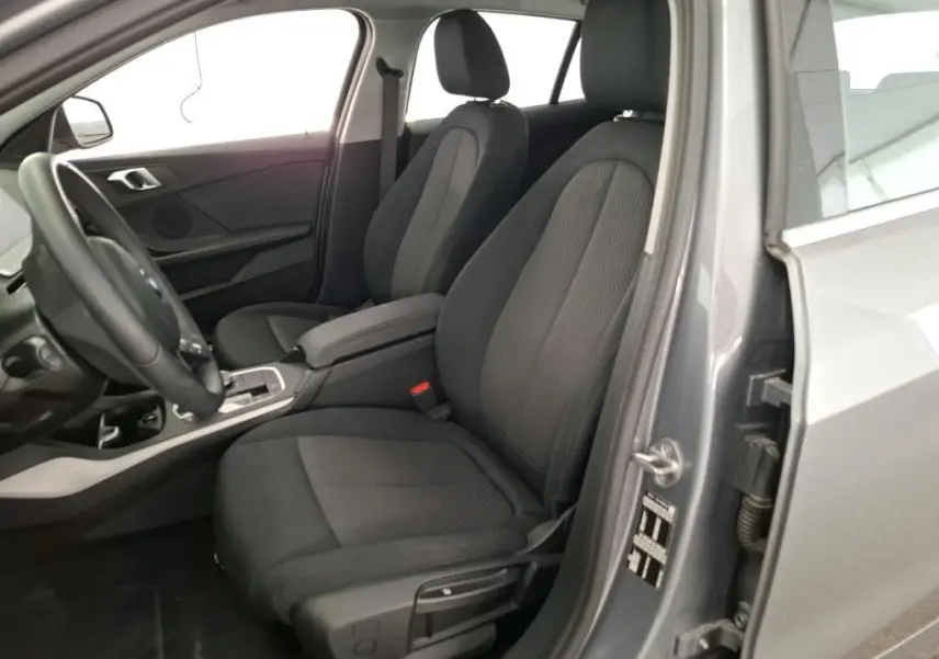 Intérieur de la BMW Série 1 116d 2022 en gris, vue côté conducteur avec sièges tissu noirs et console centrale.