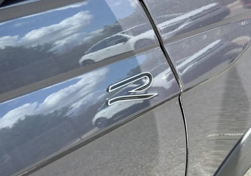 Gros plan sur l'aile avant droite gris Ascot du Volkswagen Taigo 1.0 TSI 116ch R-Line avec logo "R" chromé.