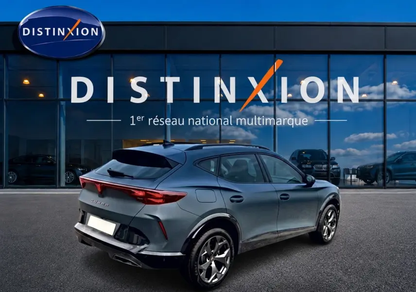 Vue 3/4 arrière droite d'un CUPRA Formentor 1.5 eTSI hybrid bleu fjord avec jantes 18 pouces devant un showroom Distinxion.