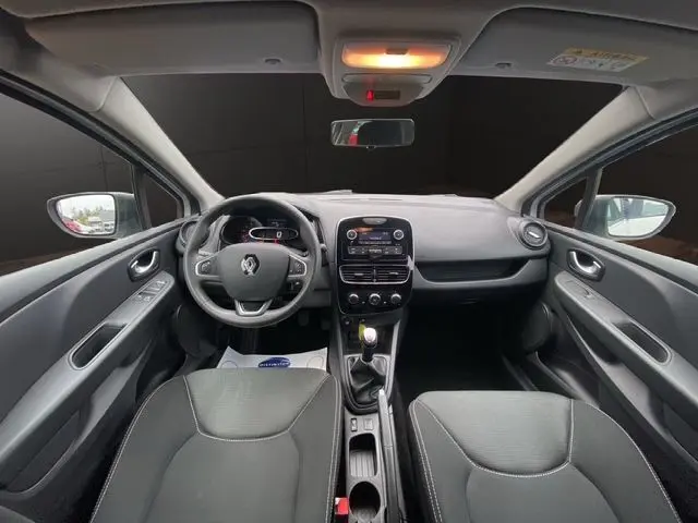 Vue intérieure avant de la Renault Clio IV blanche 2019, tableau de bord avec volant multifonction et console centrale équipée.