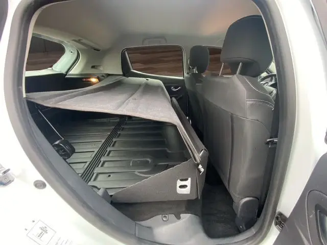 Vue intérieure côté gauche de la Renault Clio IV blanche 2019, montrant l'espace arrière et la banquette rabattue avec cache-bagages.