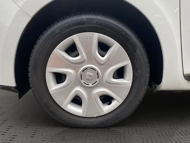 Gros plan sur la roue avant gauche d'une Renault Clio IV blanche, avec enjoliveur argenté et logo Renault central.