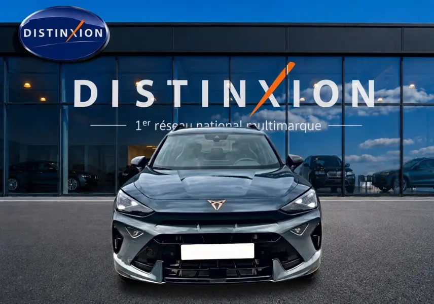Vue frontale d'un CUPRA Formentor bleu fjord 2026 avec logo cuivré et calandre sportive devant un showroom Distinxion.