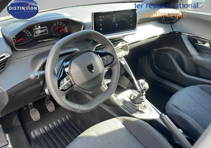 Intérieur du Peugeot 2008 2025 vu côté conducteur, montrant volant compact, tableau de bord numérique et levier de vitesse manuel.