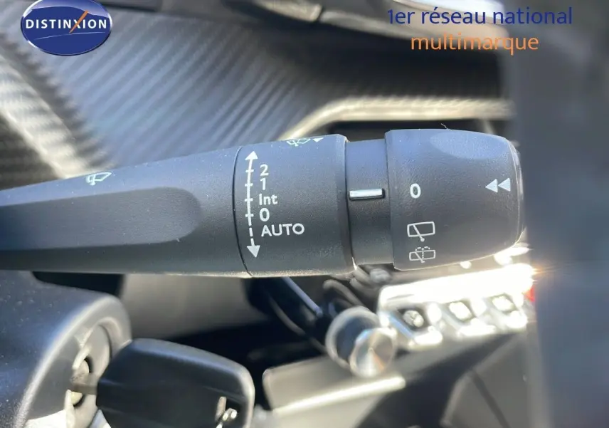Gros plan sur la commande d'essuie-glace de la Peugeot 2008 blanche, mettant en valeur les réglages automatiques.