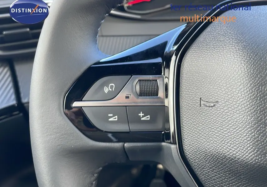 Gros plan sur les commandes du volant noir du Peugeot 2008 blanc Okenite Metal 2025 côté gauche.