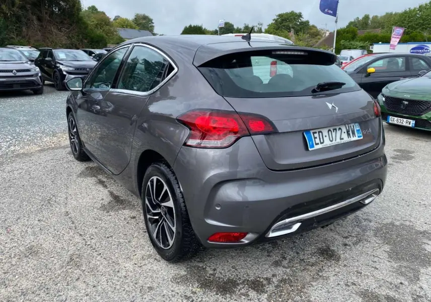 Vue 3/4 arrière droite d'une DS4 gris clair avec feux LED et jantes alliage au stationnement extérieur.