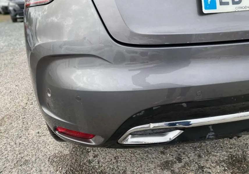 Gros plan sur le bouclier arrière gris clair du DS4 avec feu rouge et embout d'échappement chromé visible.