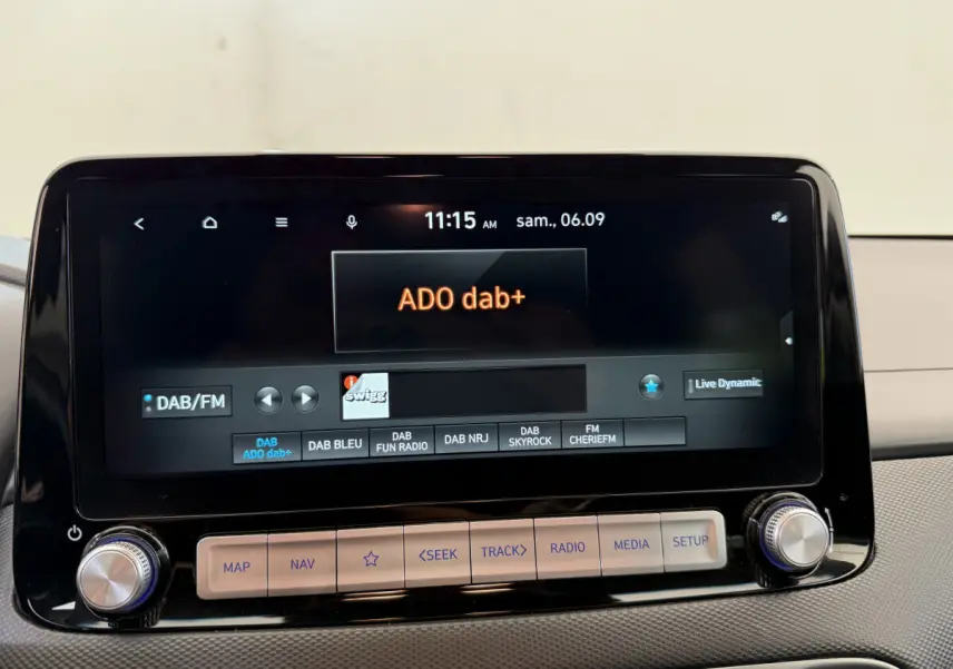 Gros plan sur l'écran tactile central du Hyundai Kona électrique gris clair, affichant la radio DAB+ ADO dab+.