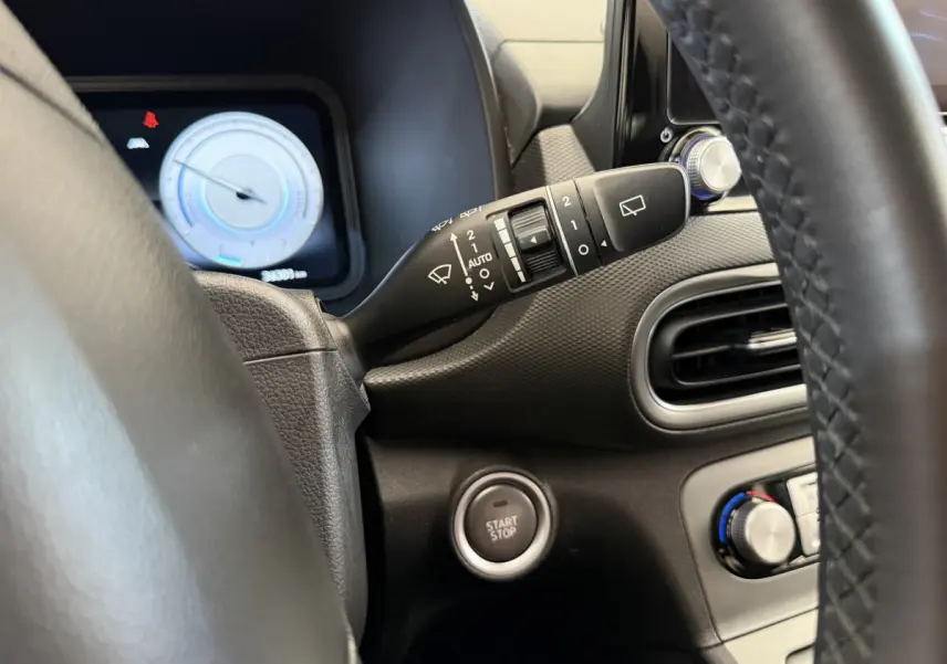 Détail du tableau de bord gris foncé du Hyundai Kona électrique 2022 avec bouton start/stop et commandes d'essuie-glace.