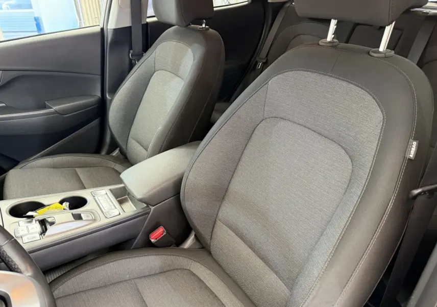 Vue intérieure rapprochée des sièges avant gris clair du Hyundai Kona électrique 2022 avec console centrale et accoudoir.