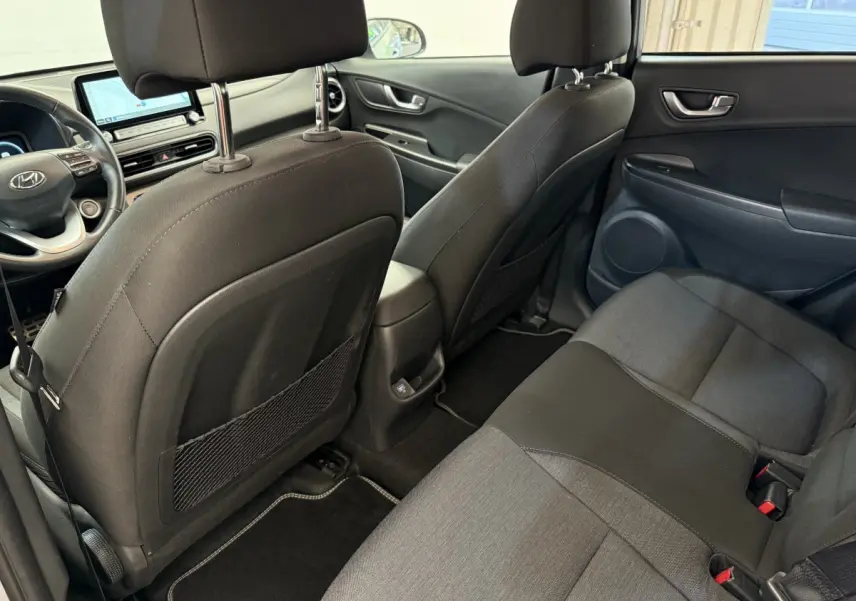 Vue intérieure arrière du Hyundai Kona électrique 2022, sièges tissu gris foncé et console centrale avec port USB.