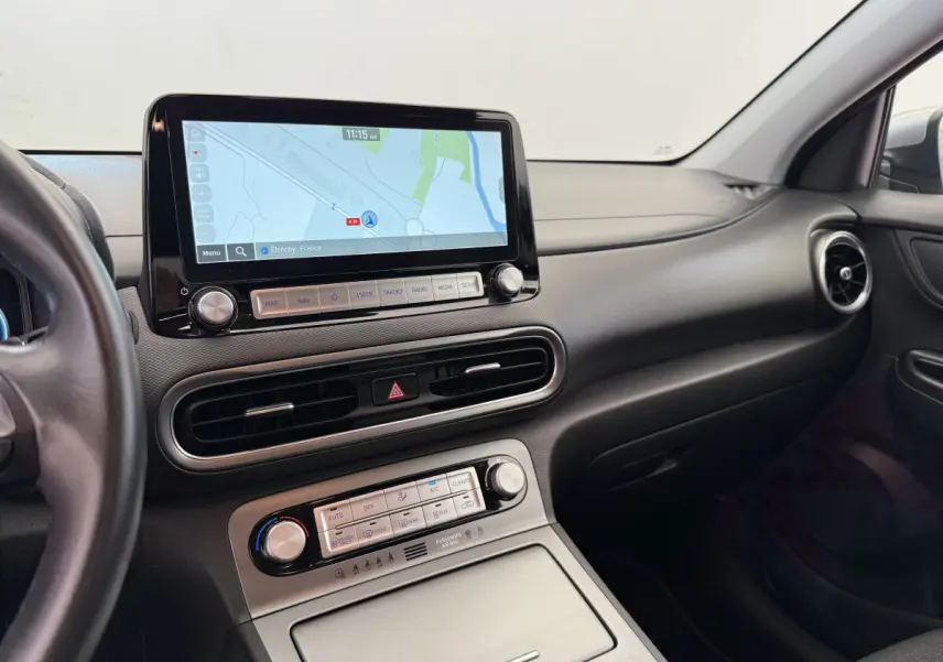 Vue intérieure côté passager du tableau de bord noir du Hyundai Kona électrique 2022 avec écran tactile de navigation allumé