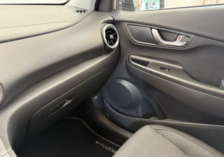 Vue intérieure côté passager du tableau de bord et porte de la Hyundai Kona électrique 2022 en gris avec détails noirs.