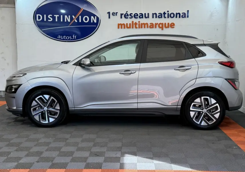 Vue latérale droite d'un Hyundai Kona gris clair électrique 2022, avec jantes modernes et toit noir contrasté.