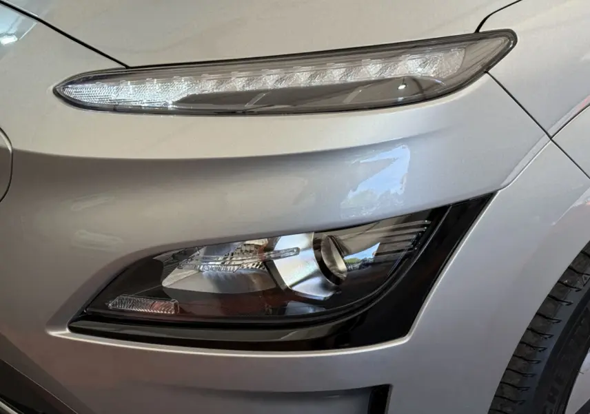 Gros plan sur le phare avant droit gris clair du Hyundai Kona électrique 2022 avec feux LED et antibrouillards intégrés.