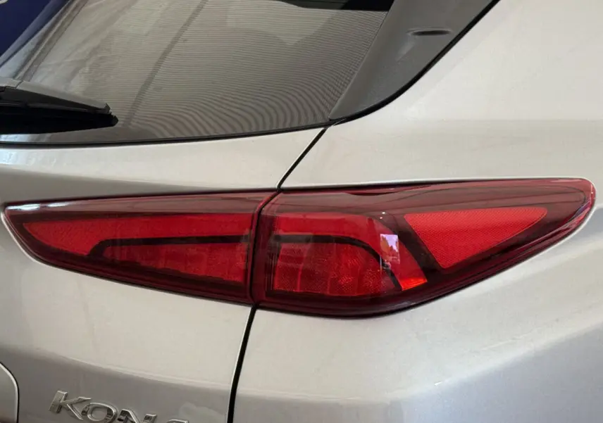 Gros plan sur le feu arrière droit rouge d'un Hyundai Kona gris clair électrique 2022, avec logo visible sur la carrosserie.