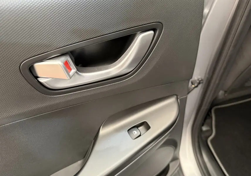 Poignée intérieure et commande de lève-vitre sur la porte avant droite du Hyundai Kona gris clair 2022 électrique.