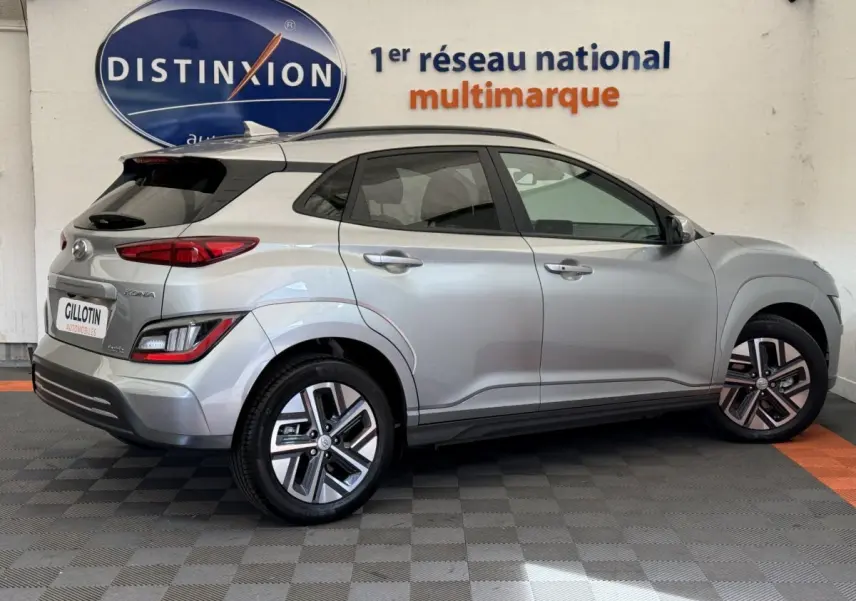 Vue latérale côté droit d'un Hyundai Kona gris clair électrique 2022 avec jantes alliage et toit noir.