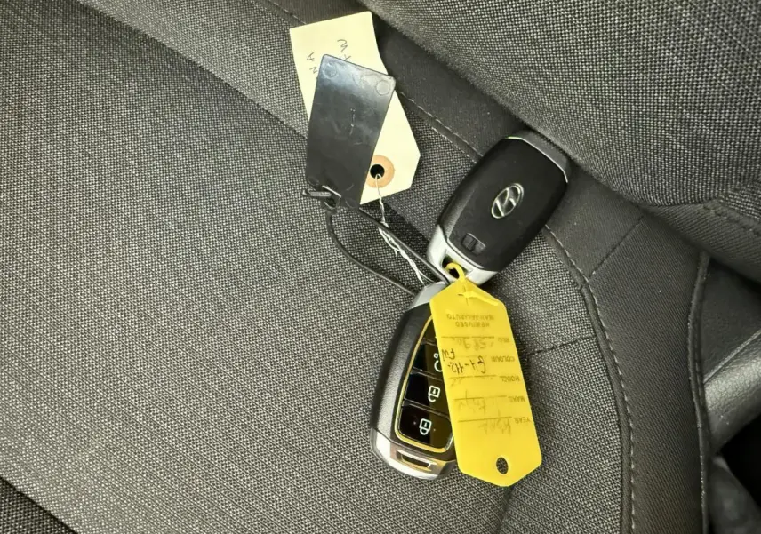 Gros plan sur les clés de contact Hyundai posées sur un siège en tissu gris foncé à l'intérieur du Kona électrique.