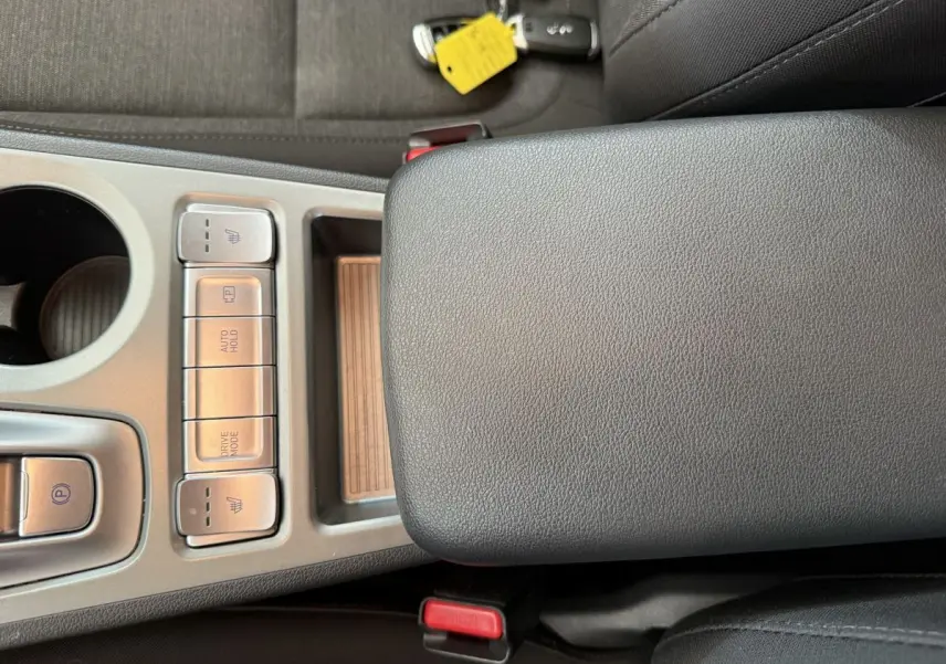 Gros plan sur la console centrale grise du Hyundai Kona électrique 2022, avec boutons chauffants et mode de conduite.