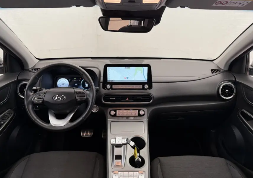 Vue intérieure frontale du tableau de bord du Hyundai Kona électrique 2022 avec écran tactile et volant cuir noir.