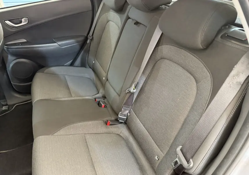 Vue côté droit de la banquette arrière grise en tissu du Hyundai Kona électrique 2022, avec ceinture de sécurité attachée.