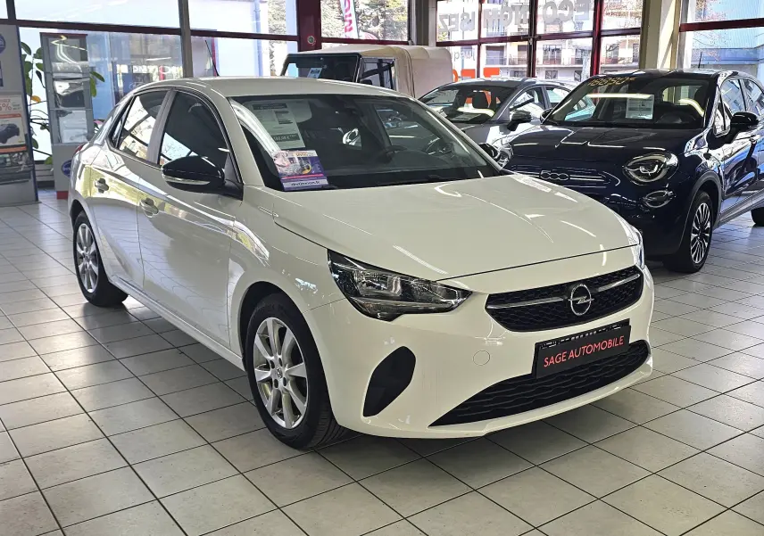 Opel Corsa blanc glacier vue 3/4 avant droit en showroom, avec jantes alliage et calandre noire.