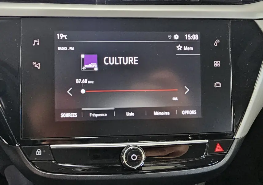 Écran tactile central de l’Opel Corsa blanc glacier 2022 affichant la radio FM sur la fréquence 87,60 MHz.