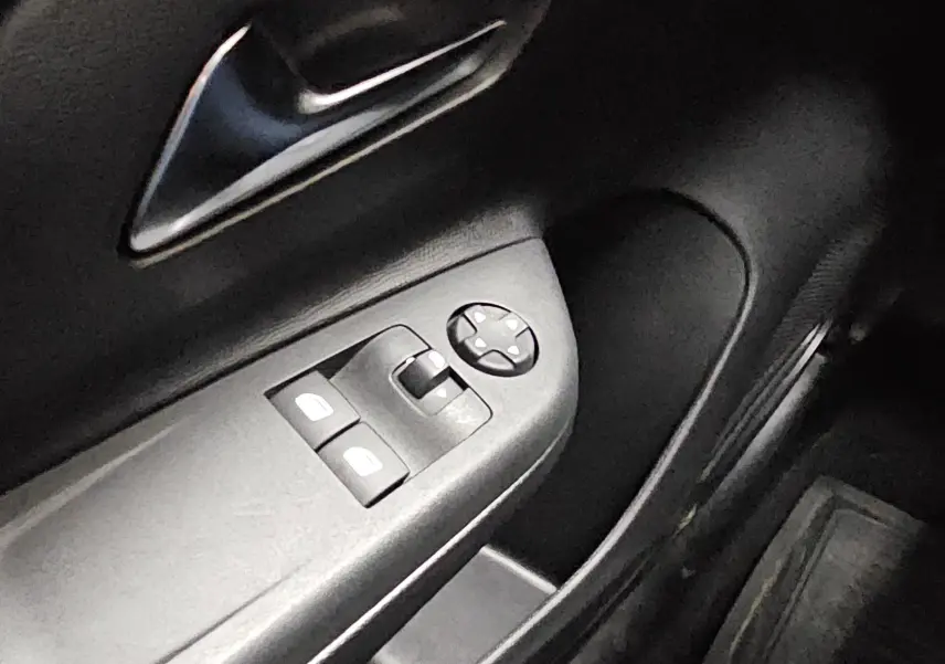 Gros plan sur la commande des vitres électriques côté conducteur de l’Opel Corsa blanc glacier 2022, intérieur noir.