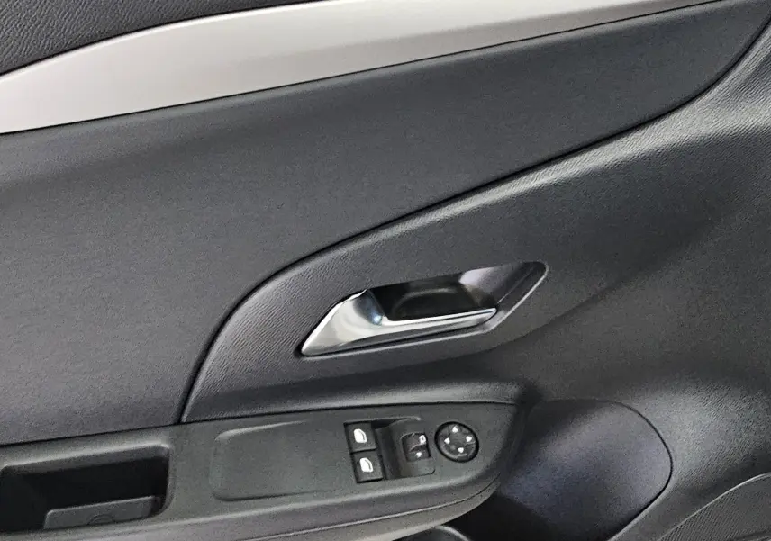 Détail de la porte côté conducteur de l’Opel Corsa blanc glacier, avec poignée chromée et commandes électriques des vitres.
