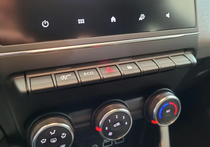 Vue rapprochée du tableau de bord central de la Renault Clio bleu, montrant les commandes de climatisation et les boutons multifonctions.