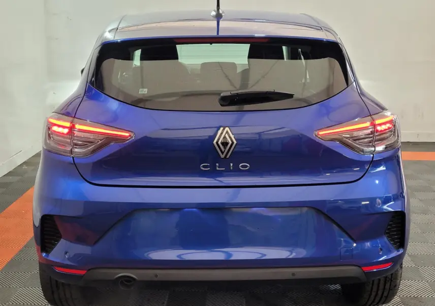 Vue arrière d'une Renault Clio bleu électrique avec feux LED allumés dans un garage intérieur.
