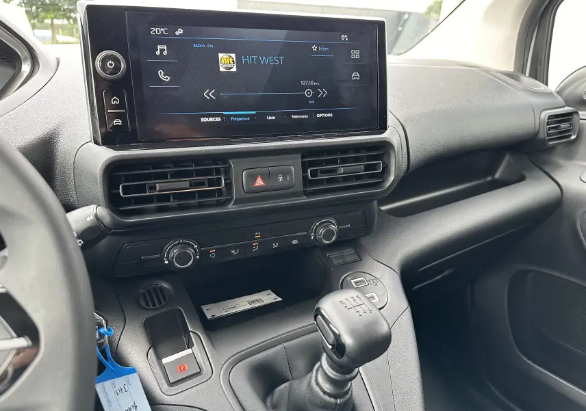 Vue intérieure du tableau de bord et levier de vitesses manuel du Peugeot Partner Fourgon blanc 2024 avec écran tactile allumé.